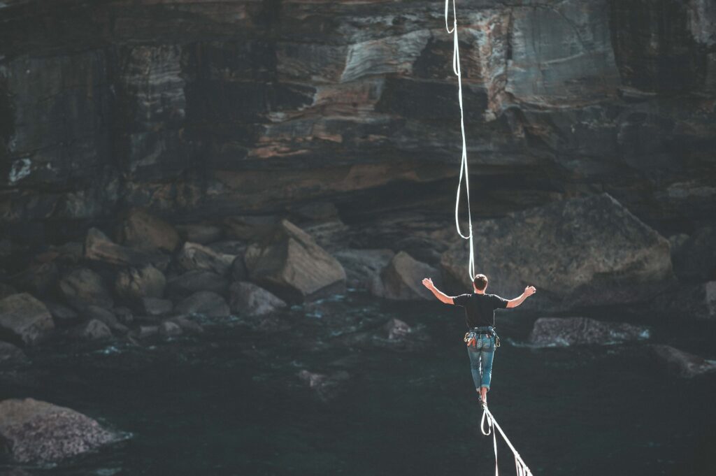 Person walking on tightrope across cliff