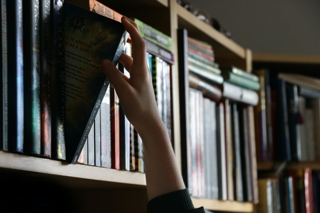 Hand reaching for a book on a shelf